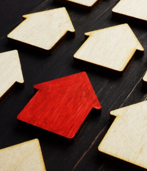 a red wooden house cutout among non colored ones